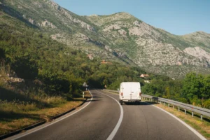 White furgon minibus driving along a winding mountain road in Albania