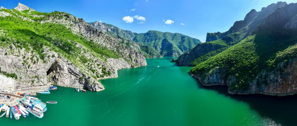 Lake Koman's emerald gorge from above, with boats moored at the jetty — the crossing at the heart of two weeks without a car in Albania
