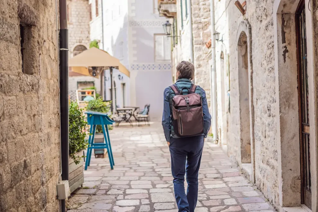 Traveler walking a cobbled lane in Kotor old town, Montenegro, carrying a single backpack