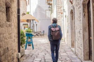Traveler walking a cobbled lane in Kotor old town, Montenegro, carrying a single backpack